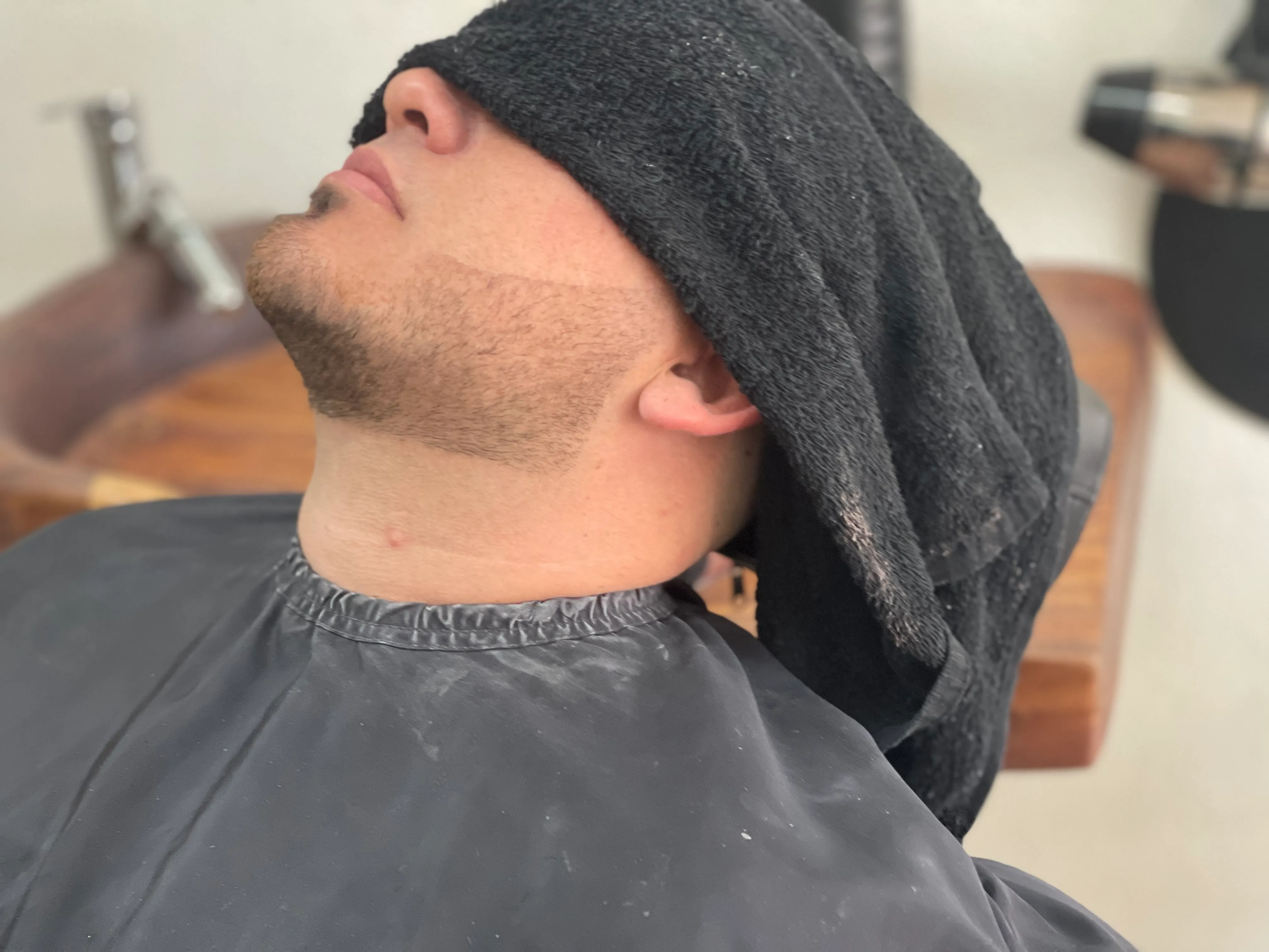 Toalla caliente sobre el rostro en el lavabo, antes del perfilado